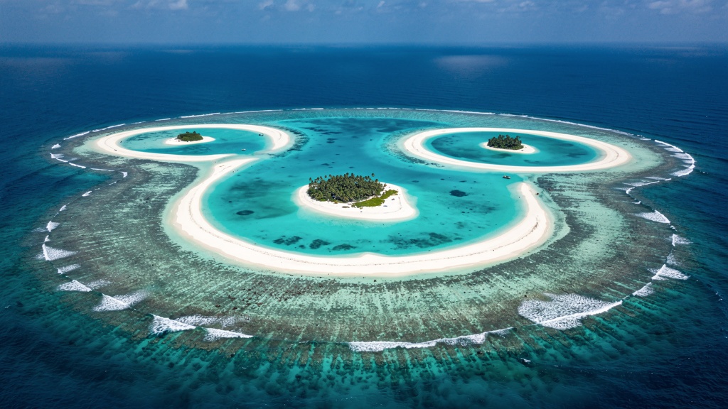 Aerial photograph of turquoise lagoons and coral islands in India’s Lakshadweep archipelago.